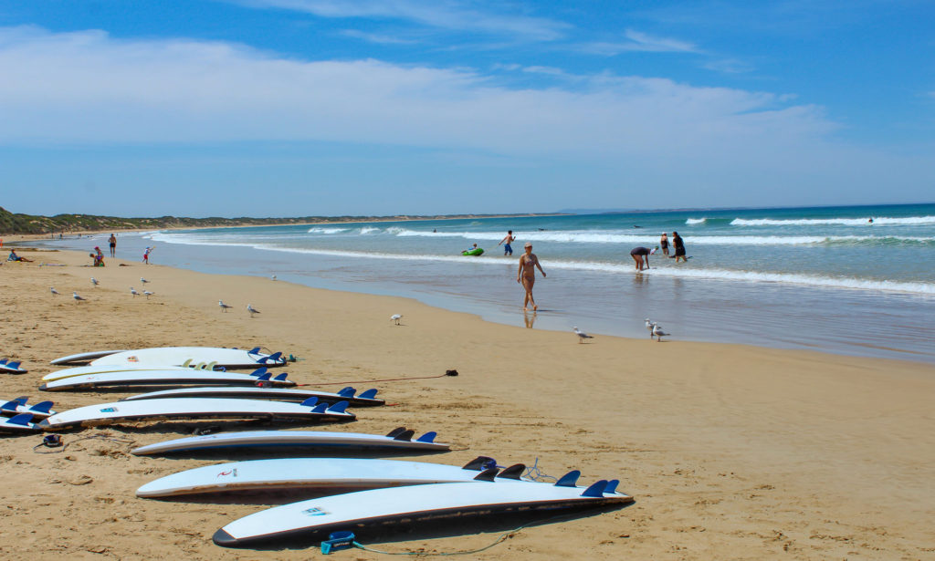 A line of surfboards lies on the beach on a summers day